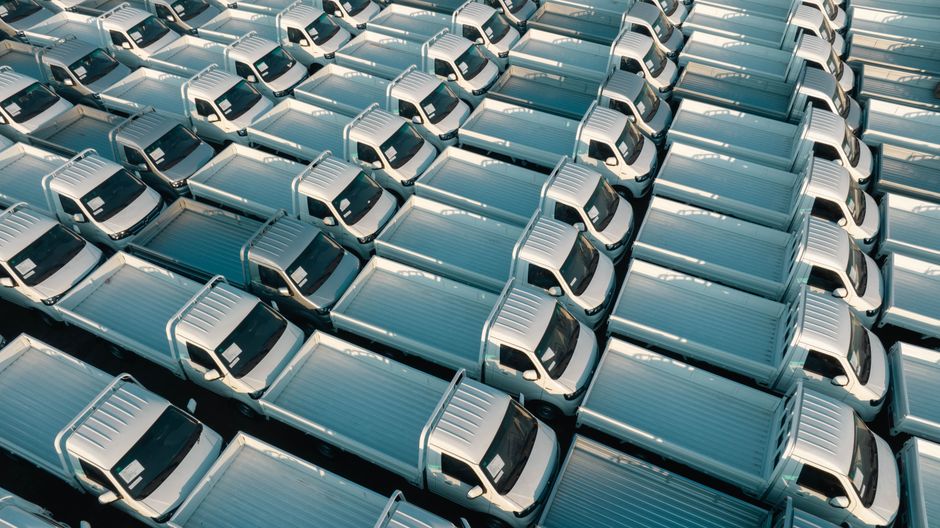 A top-down view of numerous white trucks parked in a grid pattern, showing symmetry and industrial logistics.